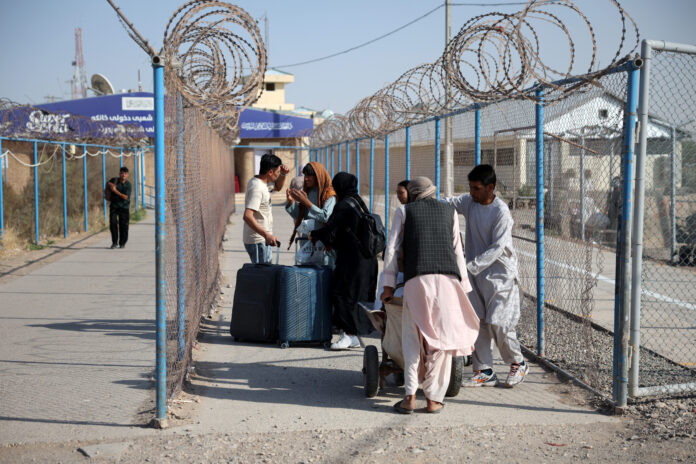Afghan nationals carrying their belongings walk after crossing the border from Iran at the Islam Qala border crossing